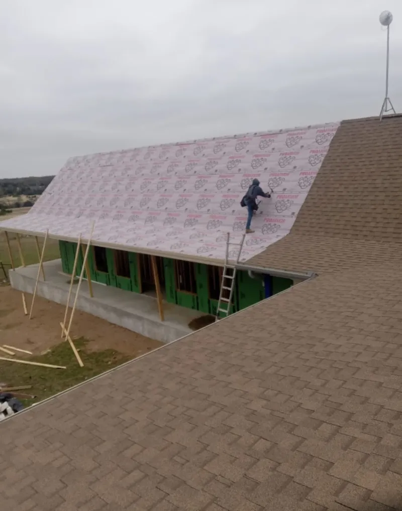Worker preparing underlayment for a metal roof installation in Brick